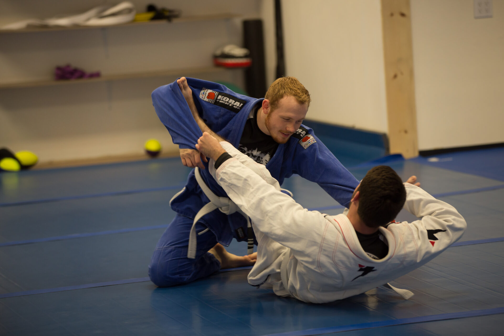 Two men are practicing judo on a blue floor.