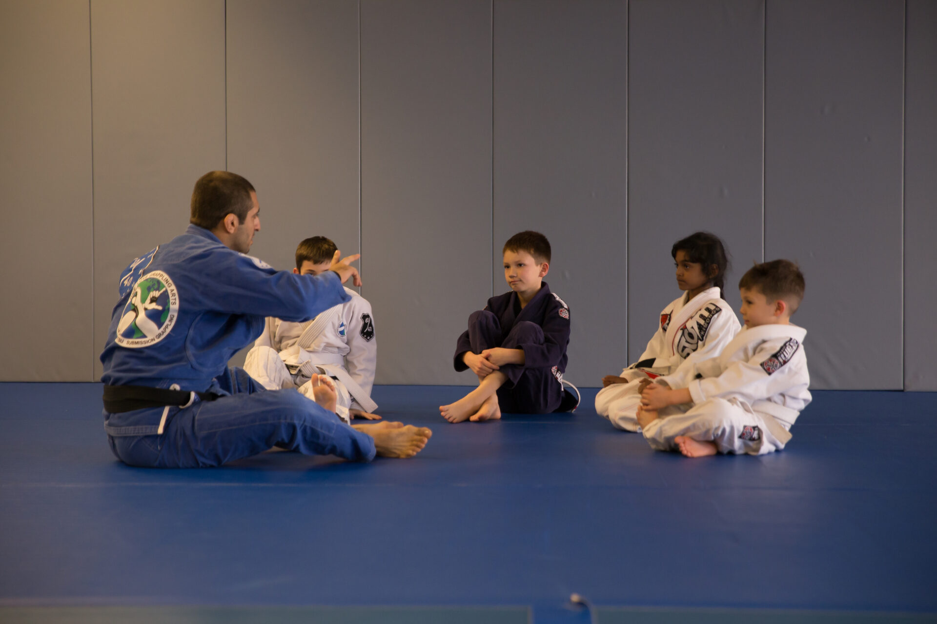 A group of kids sitting on the ground with their trainer.