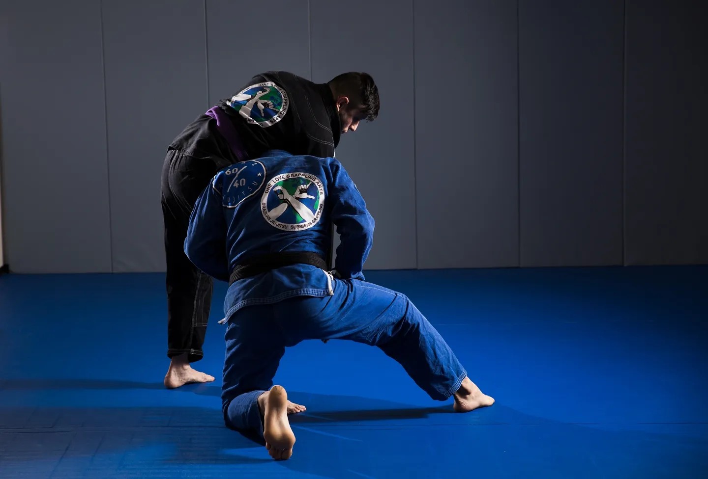 Two men in blue and black uniforms practicing bjj.