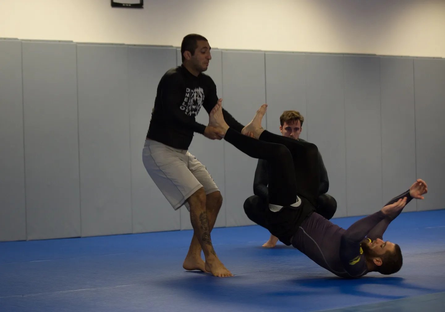 Two men are practicing martial arts on a blue floor.