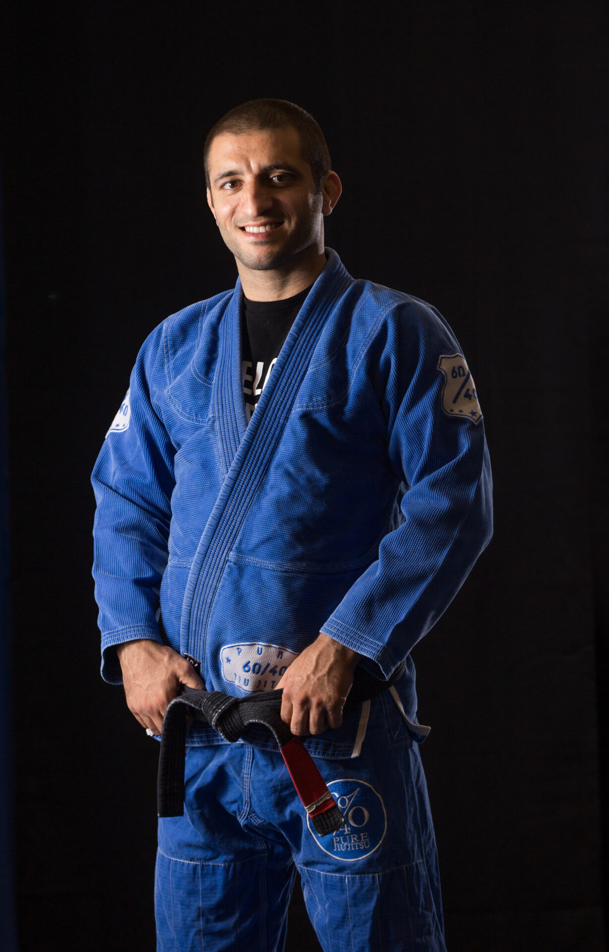 A man in blue and black uniform holding a red belt.