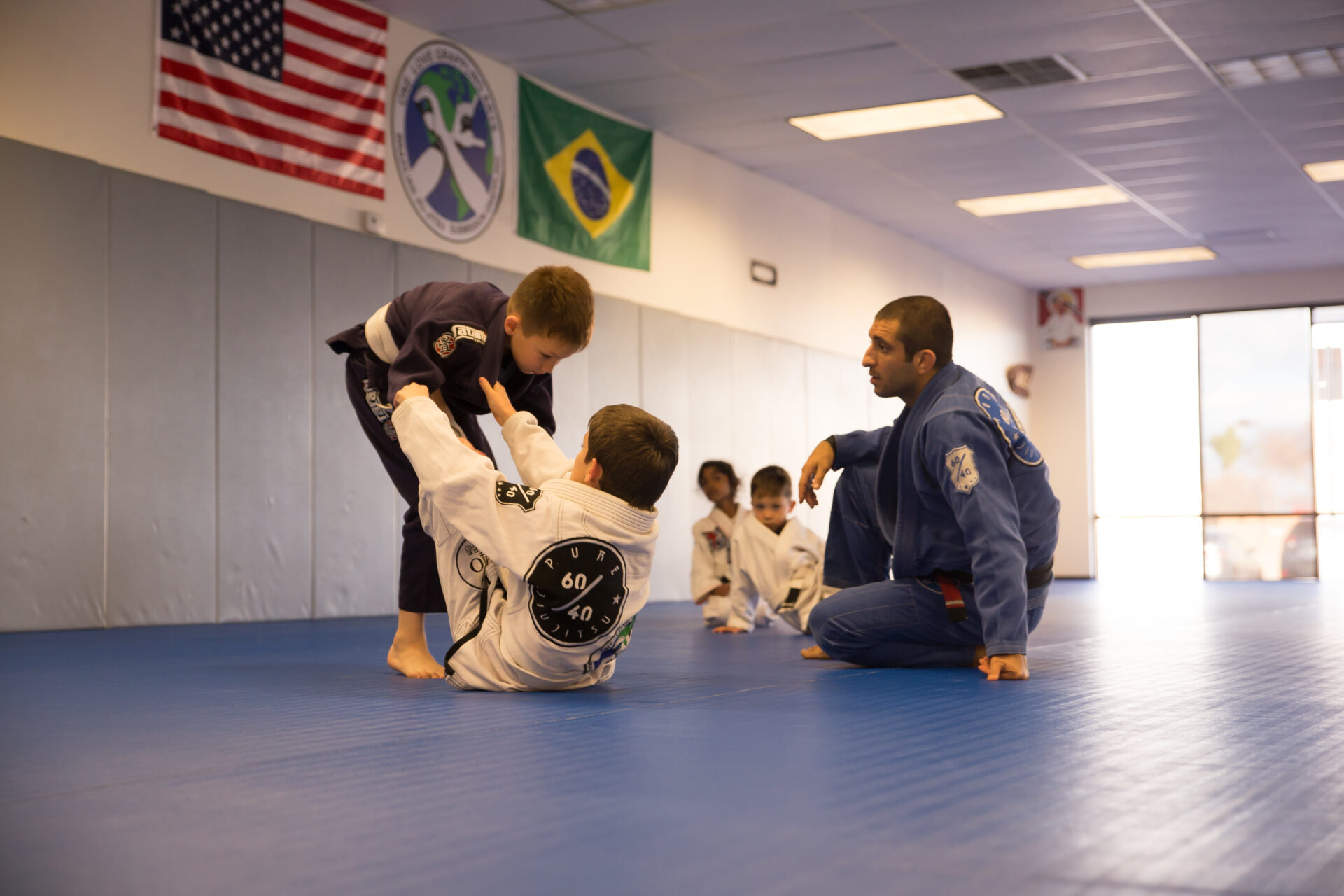 A group of kids practicing jiu jitsu in the gym.